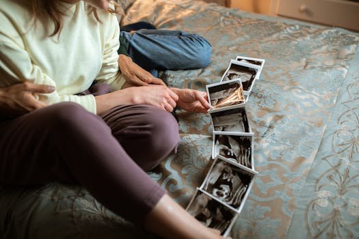 Expectant parents sit on a bed sharing ultrasound photos, symbolizing family love and anticipation.